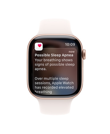Apple Watch Series 11 z kopertą z aluminium w kolorze różowego złota, pasek sportowy w kolorze łagodnego różu, rozwinięte powiadomienie o bezdechu sennym, prawy bok urządzenia, pokrętło Digital Crown