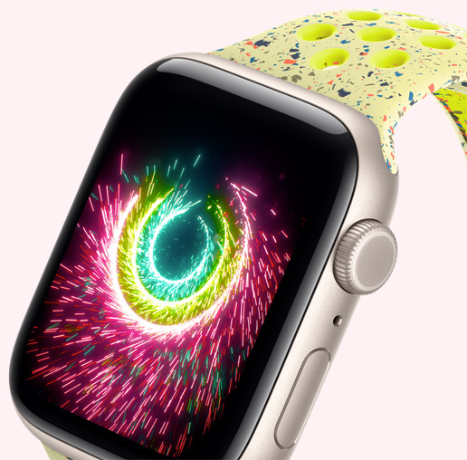 Apple Watch SE 3, aluminiumboett i färgen stjärnglans, aktivitetsringar som gnistrar som fyrverkerier, Nike-sportband i färgen Volt Splash