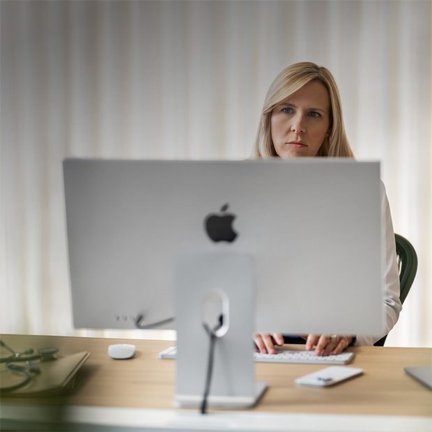 Một nhân viên y tế nhìn vào màn hình iMac trên bàn làm việc.