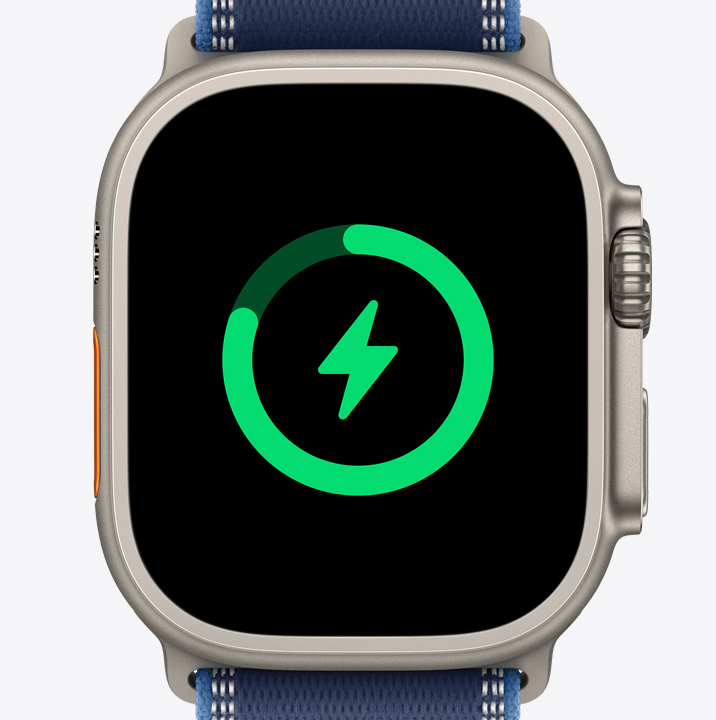 Apple Watch Ultra 3 med urkasse av naturlig titan viser et ladesymbol på skjermen.