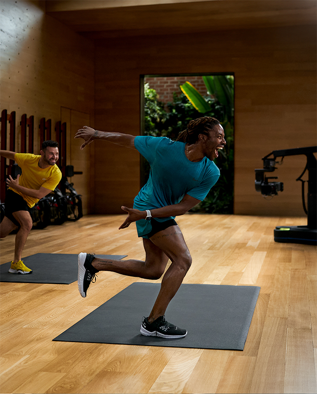 Instruktører fra Apple Fitness+ leder en treningsøkt foran kameraene i et TV-studio. 