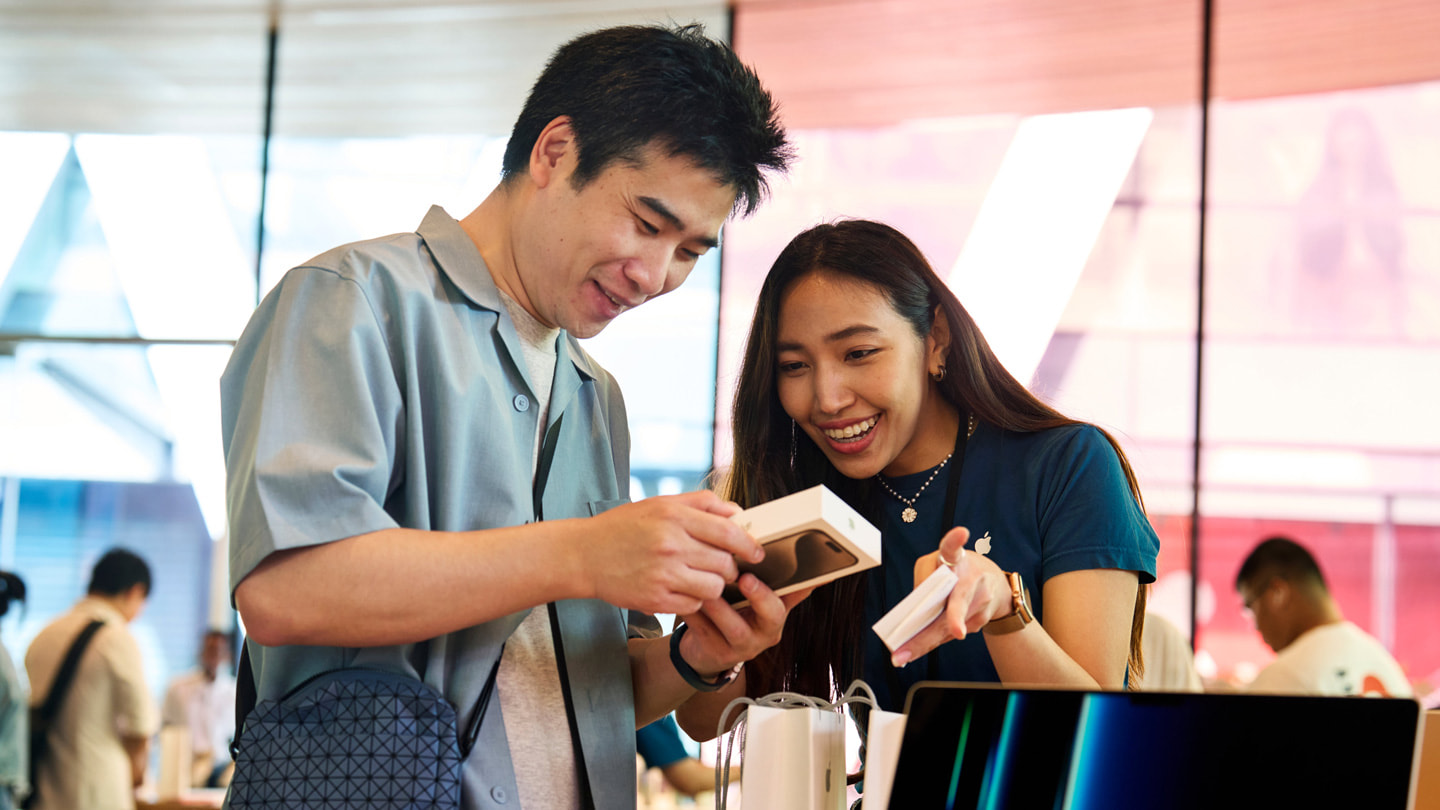 Khách hàng đang mở hộp điện thoại iPhone 15 Pro mới với sự hỗ trợ của nhân viên trong cửa hàng Apple Central World.