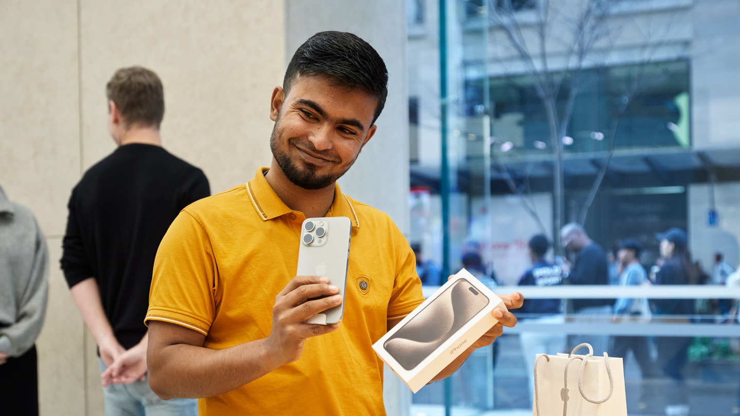 Khách hàng vui vẻ khoe điện thoại iPhone 15 Pro mới bên trong cửa hàng Apple Sydney, Úc.