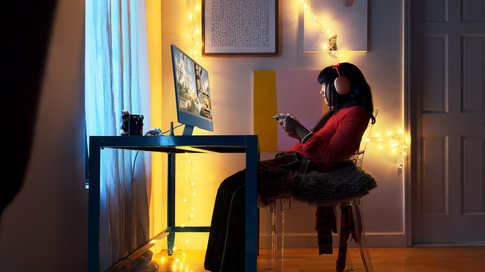 En gamer bruker nye iMac med M3-chip og AirPods Max i rød.