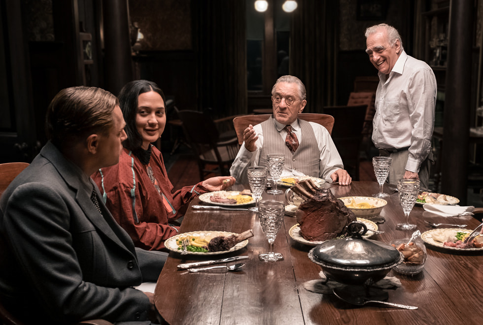 A behind-the-scenes still from “Killers of the Flower Moon” shows Leonardo DiCaprio, Lily Gladstone, Robert De Niro and Martin Scorsese around a dining table.
