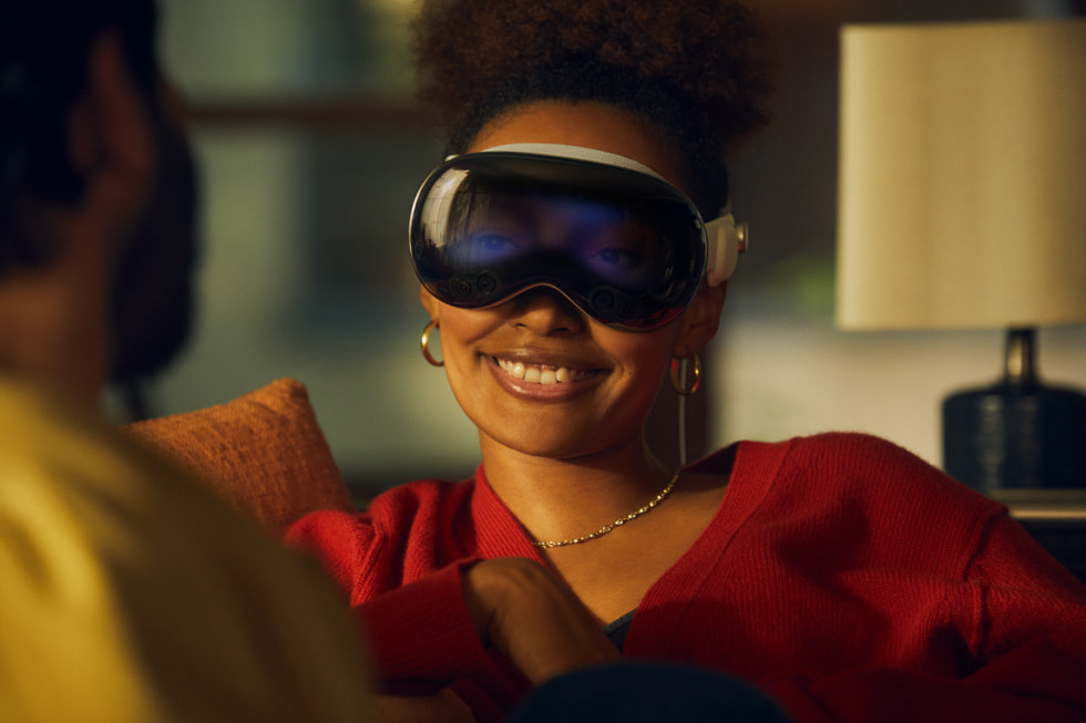 Una persona con el Apple Vision Pro mientras habla con otra persona, con la funcionalidad EyeSight que muestra los ojos del usuario en el dispositivo.