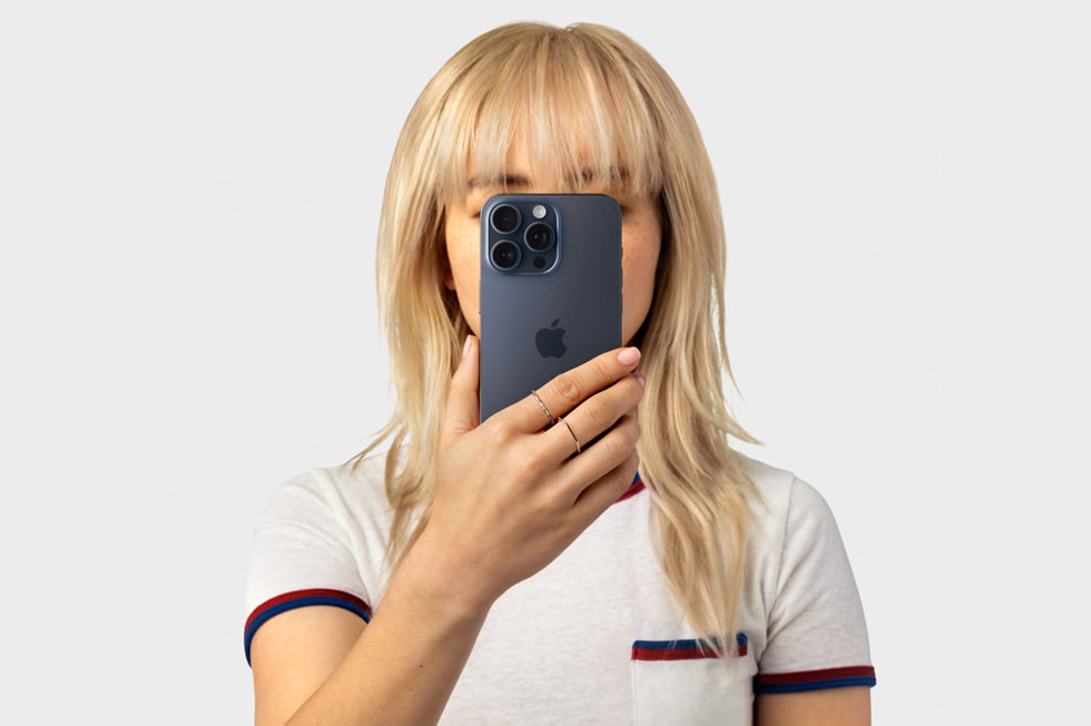 iPhone 15 Pro’yu yüzüne doğru tutan bir kişi.