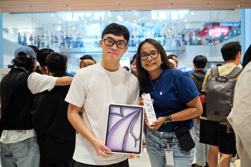 Seorang pelanggan dengan anggota tim Apple memamerkan iPad Air dan Apple Pencil Pro yang baru ia beli.