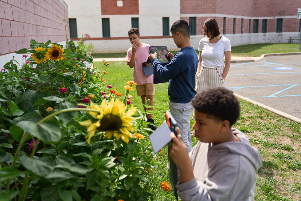Los participantes del campamento STEM Explorers usan la cámara del iPad en un jardín.