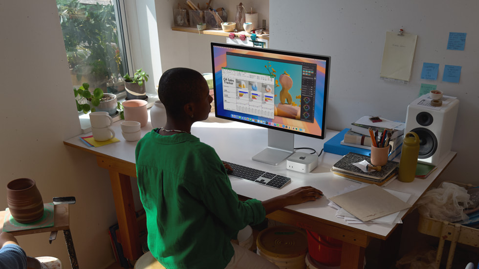 Une personne utilise un Mac mini sur un bureau entouré par des créations en céramique.