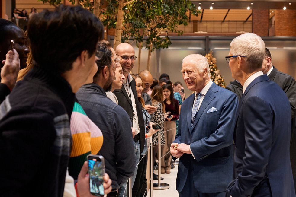 Le roi Charles et Tim Cook saluant des personnes dans les bureaux d’Apple Battersea.