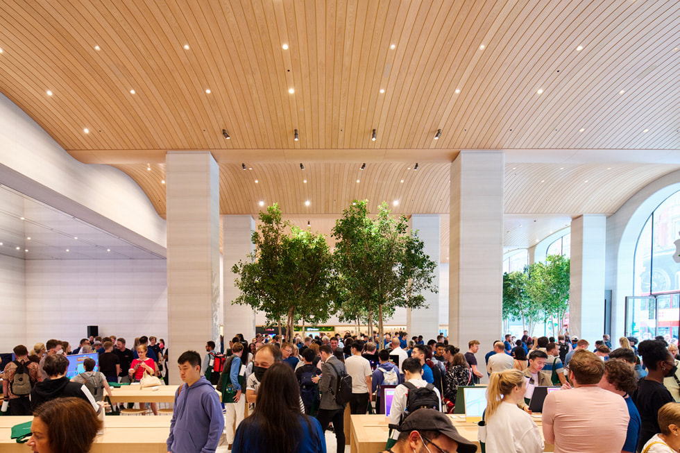 Szeroki kadr pokazujący tłum klientów w sklepie Apple Brompton Road, w którym przy wejściu i oknach stoją sycylijskie figowce.