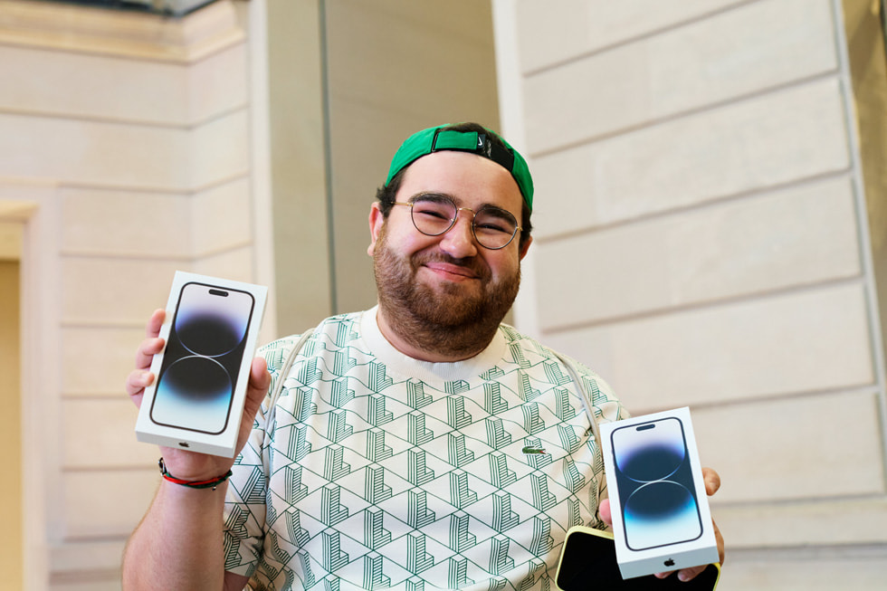 En kunde som står utenfor Apple Champs-Élysées og ser på et utstillingsvindu med forskjellige iPhone-enheter.