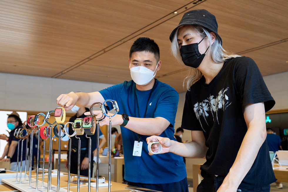 Et teammedlem i Apple Sanlitun viser Apple Watch-enheter til en kunde.
