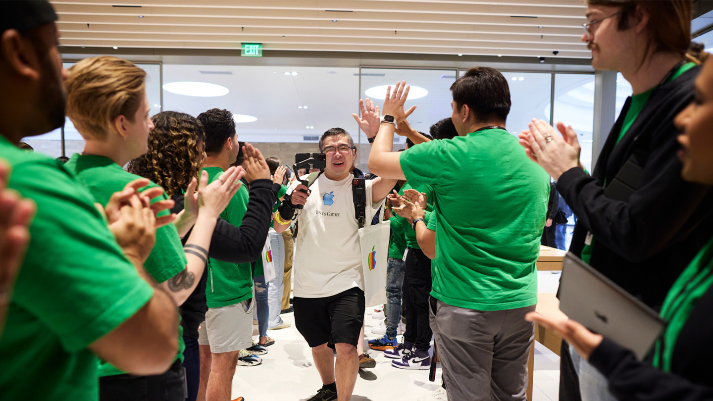 Viser kunder som går inn i Apple Tysons Corner mens ansatte klapper.