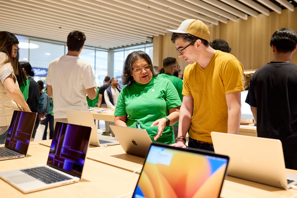 En ansatt viser en kunde de nyeste Mac-modellene.