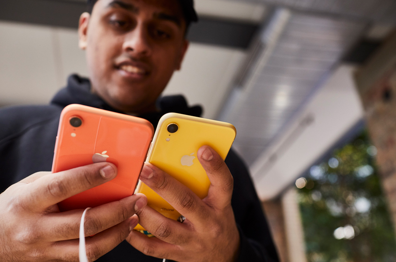 コーラルとイエローのiPhone XRを見比べているお客様。 