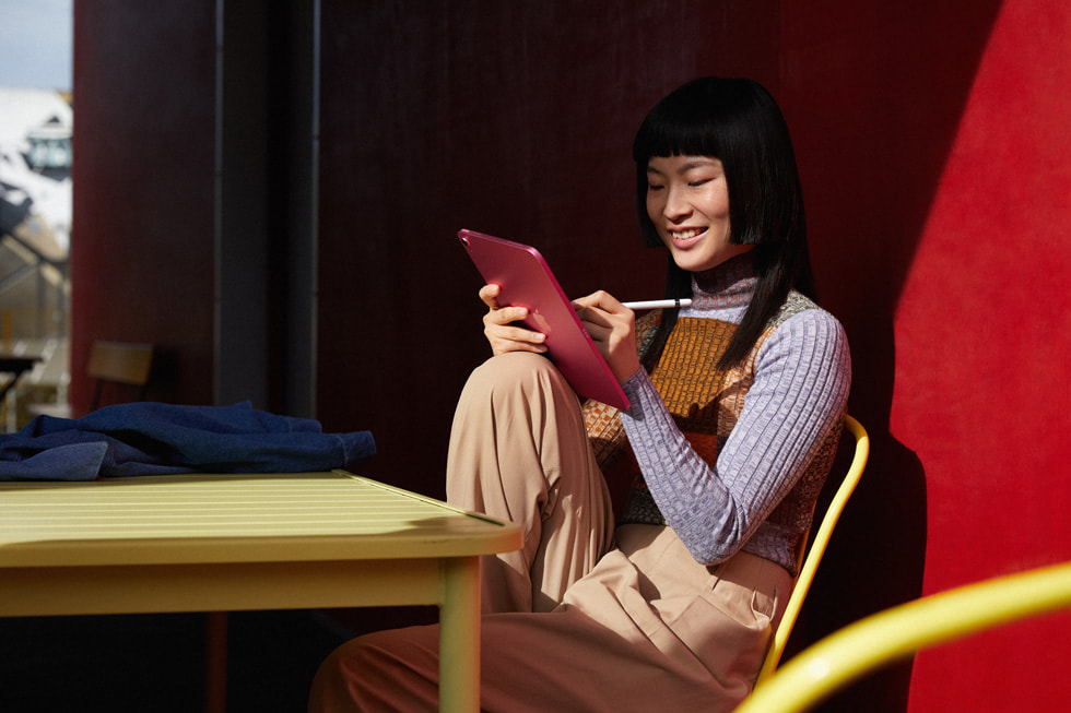 Een vrouw die werkt met Apple Pencil op iPad in roze uitvoering.