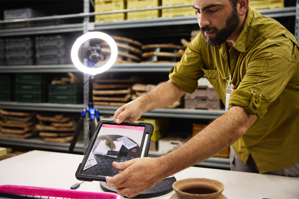 El Dr. Badillo inclina un iPad Pro sobre una máscara en una oficina.