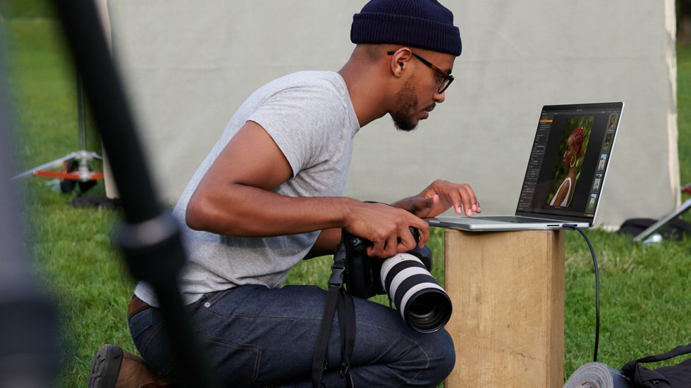 En fotograf, der bruger MacBook Pro til at redigere billeder udendørs.
