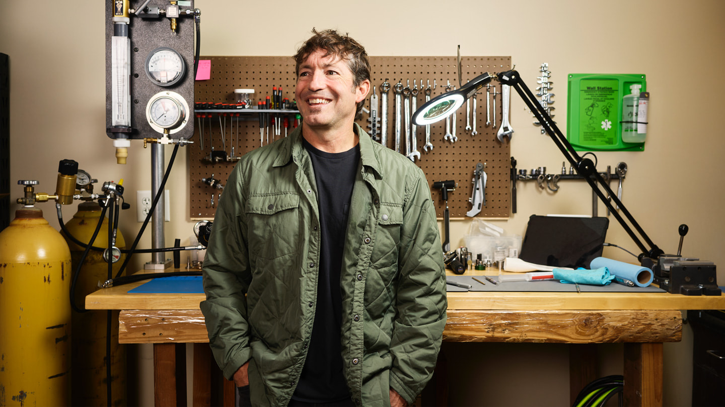 Huish Outdoors CEO Mike Huish 站在工作檯前，檯上擺放了一系列工具及潛水裝備。 