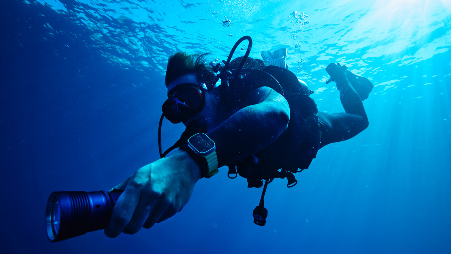 一名潛水員佩戴備有《Oceanic+》app 的 Apple Watch Ultra，在海面下游泳。