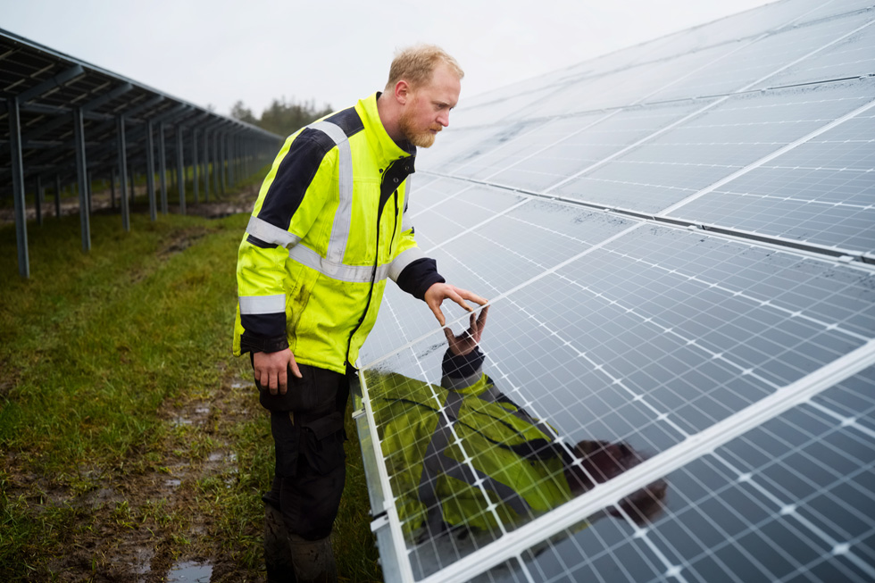 Ein Arbeiter untersucht eine Solaranlage.